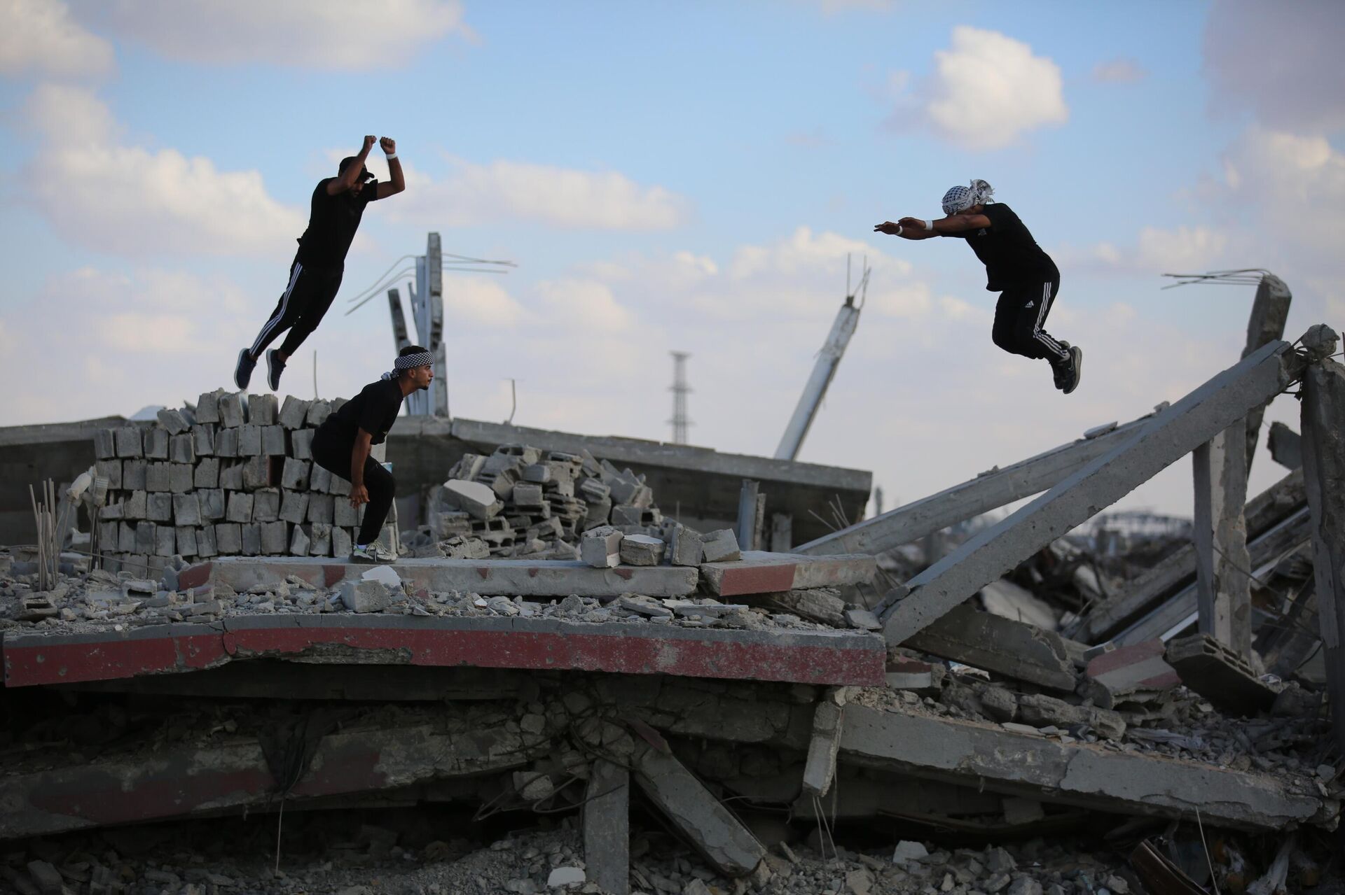 Молодые палестинские спортсмены демонстрируют элементы паркура среди руин разрушенных зданий в районе Аль-Муграка после прекращения огня в городе Газа - Sputnik Монгол Улс, 1920, 15.10.2025