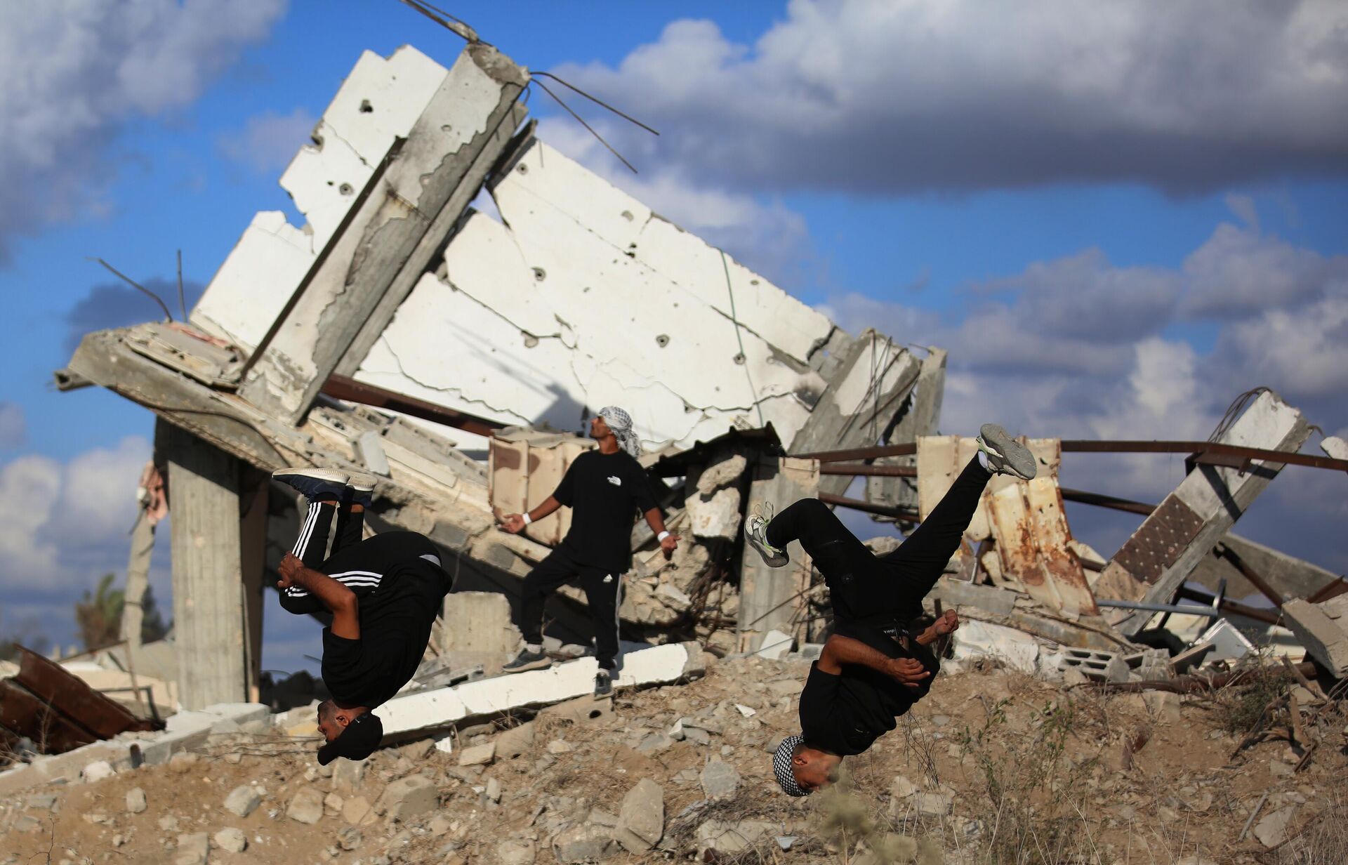 Молодые палестинские спортсмены демонстрируют элементы паркура среди руин разрушенных зданий в районе Аль-Муграка после прекращения огня в городе Газа - Sputnik Монгол Улс, 1920, 15.10.2025