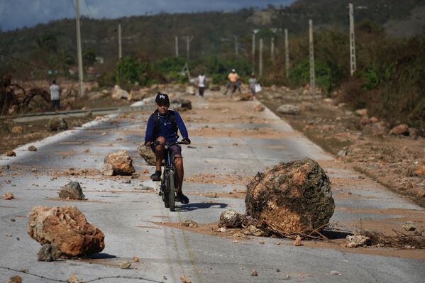 2025 оны 10-р сарын 30-ны Пүрэв гарагт Сантьяго де Кубын өмнөд эрэгт болсон Мелисса хар салхины дараа гудамжны нуранги дээгүүр дугуй унаж буй хүү. (AP Зураг/Ramón Espinosa) - Sputnik Монгол Улс