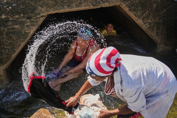 2025 оны 10-р сарын 30-ны Пүрэв гарагт Сантьяго де Кубагийн өмнөд эргээс дайран өнгөрсөн Мелисса хар салхинд нэрвэгдсэн голд хүмүүс хувцсаа угааж байна. (AP Зураг/Ramón Espinosa) - Sputnik Монгол Улс