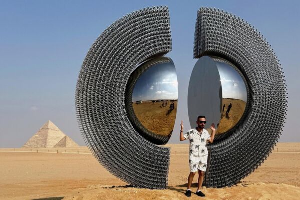 2025 оны 11-р сарын 11-ний Мягмар гарагт Египетийн Гиза хотын Гиза пирамидуудын түүхэн дурсгалт газарт болсон "Forever Is Now" орчин үеийн урлагийн тав дахь үзэсгэлэнгийн үеэр Туркийн зураач Мерт Аге Косегийн "Шен" инсталляцийн хамт нэгэн зочин зургаа авахуулж байна. (AP Photo/Mayar Mokhtar) - Sputnik Монгол Улс