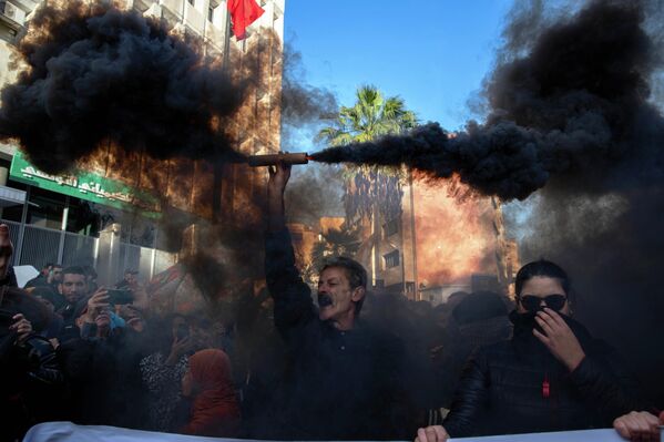 Тунис, Тунис хот — 2025 оны 11-р сарын 22-ны Бямба гарагт зохион байгуулагдсан эсэргүүцлийн үеэр нэгэн эр утааны дохио барьж, өмнөд нутгийн фосфатын үйлдвэрээс үүссэн байгаль орчны бохирдлыг эсэргүүцэж байна. Эсэргүүцлийн арга хэмжээ нь Ерөнхийлөгч Каис Саидын засаглалыг шүүмжлэх, улс төрийн хоригдлуудыг суллахыг шаардах зорилготой байлаа. (AP/Анис Мили) - Sputnik Монгол Улс