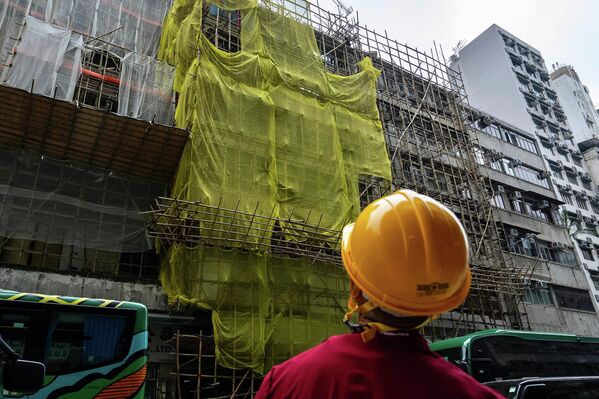 2025 оны 12-р сарын 4-ний Пүрэв гарагт Хонконгийн Шинэ нутаг дэвсгэрийн Тай По дүүргийн Ван Фук шүүхэд гарсан галын дараа Монг Кок дүүрэгт засвар хийгдэж буй барилгын ойролцоо барилгын ажилчин зогсож байна. (AP Photo/Chan Long Hei) 2025 оны 12-р сарын 4-ний Пүрэв гарагт Хонконгийн Шинэ нутаг дэвсгэрийн Тай По дүүргийн Ван Фук шүүхэд гарсан галын дараа Монг Кок дүүрэгт засвар хийгдэж буй барилгын ойролцоо барилгын ажилчин зогсож байна. (AP Photo/Chan Long Hei) - Sputnik Монгол Улс