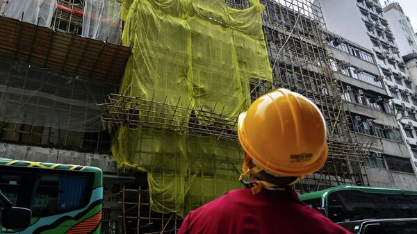 Хонконгийн Монг Кок дахь галын дараа засвар хийгдэж буй барилгын ойролцоо барилгын ажилчин зогсож байна. - Sputnik Монгол Улс