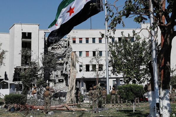 2025 оны 7-р сарын 19-ний Бямба гарагт Сирийн Дамаск хотод Батлан ​​​​хамгаалах яамны барилгын өмнө Сирийн цэргүүд төрийн далбаагаа мандуулж байна. Энэ барилга лхагва гарагт Израилийн агаарын цохилтод ихээхэн хохирол амссан байв. (AP Photo/Omar Sanadiki) - Sputnik Монгол Улс