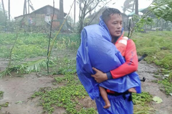 Филиппиний эргийн харуулын өгсөн энэ зураг дээр 2025 оны 9-р сарын 22-ны Даваа гарагт Филиппиний хойд хэсгийн Кагаян мужийн Санта Ана хотод "Рагаса" хар салхи дэгдэж байгаа үед аврагч хүүхдийг аюулгүй газар руу нүүлгэн шилжүүлж байна. (Филиппиний эргийн харуулын алба AP-ээр дамжуулан) - Sputnik Монгол Улс