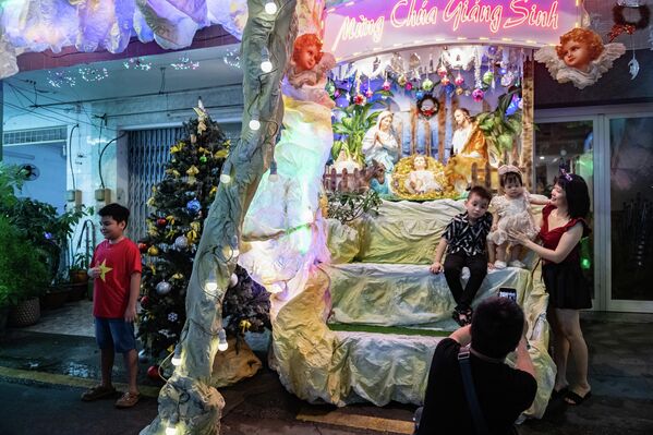 Вьетнамын Хо Ши Мин хот - 12-р сарын 24: 2025 оны 12-р сарын 24-ний өдөр Вьетнамын Хо Ши Мин хотод Христийн мэндэлсний баярын өмнөх өдөр хүмүүс Христийн мэндэлсний баярын үзэгдлээр чимэглэсэн байшингийн өмнө зураг авч байна. Вьетнамд Христийн мэндэлсний баяр бол нийтийн баяр биш боловч олон хүн үүнийг баярын арга хэмжээ болгон тэмдэглэдэг. Католик нийгэмлэгүүдэд оршин суугчид амьдардаг нарийн гудамжаа гэрэл, Христийн мэндэлсний баярын үзэгдлүүд болон шашны бэлгэдлээр чимэглэдэг. Христийн мэндэлсний баярын үеэр эдгээр гудамжууд нь баярын нийтлэг орон зай болж, бусад газраас ирсэн зочдыг татдаг. (Зураг: Тань Хью/Getty Images) - Sputnik Монгол Улс