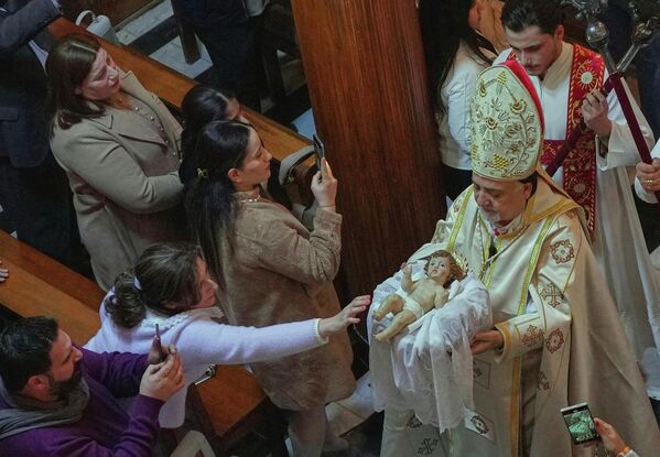 Иракийн Христэд итгэгчид 2025 оны 12-р сарын 24-ний Лхагва гарагт Иракийн Багдад хотын төвд байрлах Авралын хатагтайн сүмд Зул сарын баярын өмнөх үдэшлэгт оролцож байна. (AP Photo/Hadi Mizban) - Sputnik Монгол Улс