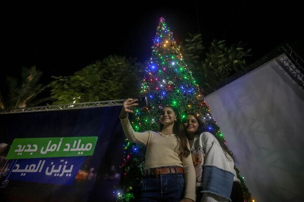  Газа - 2025 оны 12-р сарын 24-нд Газын Латин сүмд (Ариун гэр бүлийн сүм) Зул сарын баярын цуглаанд оролцож буй хүмүүс зул сарын гацуур модны өмнө зургаа авахуулж байна. (Зураг: Саид М. М. Т. Жарас/Anadolu via Getty Images) - Sputnik Монгол Улс